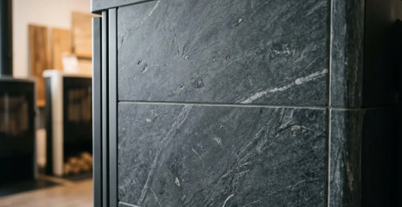 Détail rapproché habillage en pierre ollaire gris anthracite d'un poêle à accumulation, texture naturelle et veines caractéristiques visibles